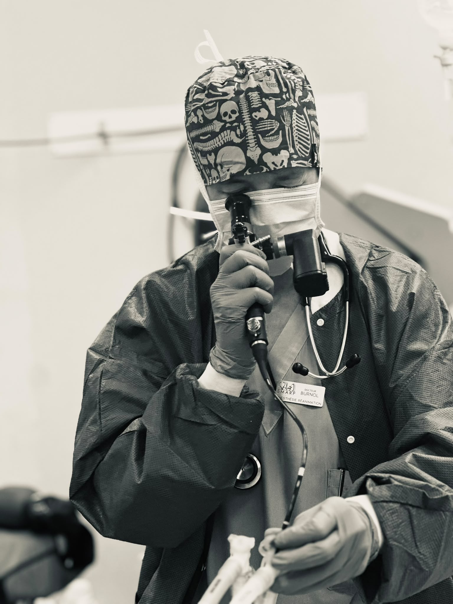 Médecin anesthésiste-réanimateur en tenue de bloc, masque et calot, vérifiant un fibroscope avant l'induction